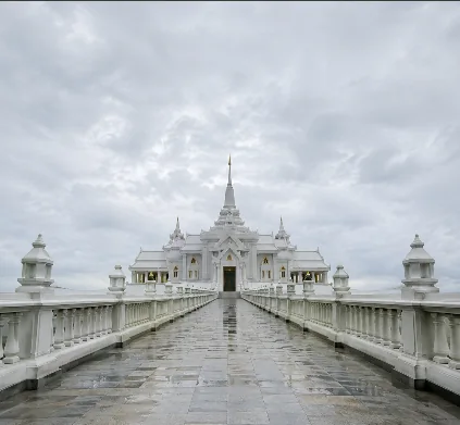 A white Thai temple at the end of a rain-wet causeway, shot on location in Phuket